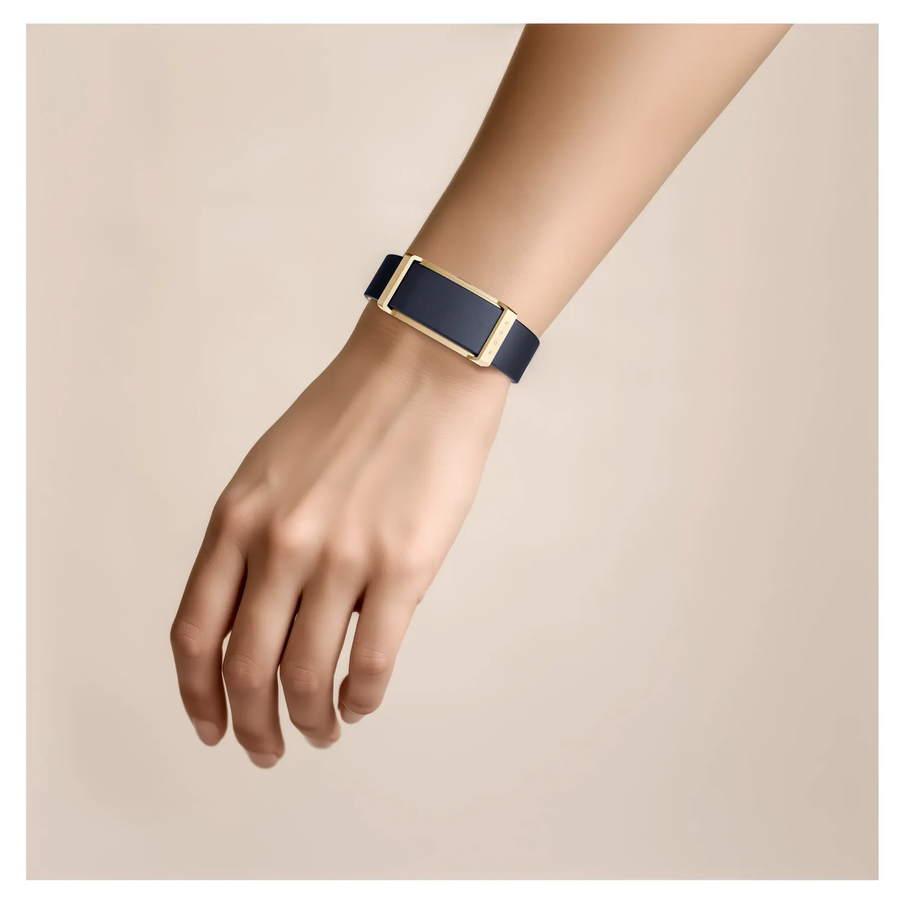 Un poignet porte un bracelet connecté Fascine Paris bleu nuit et or