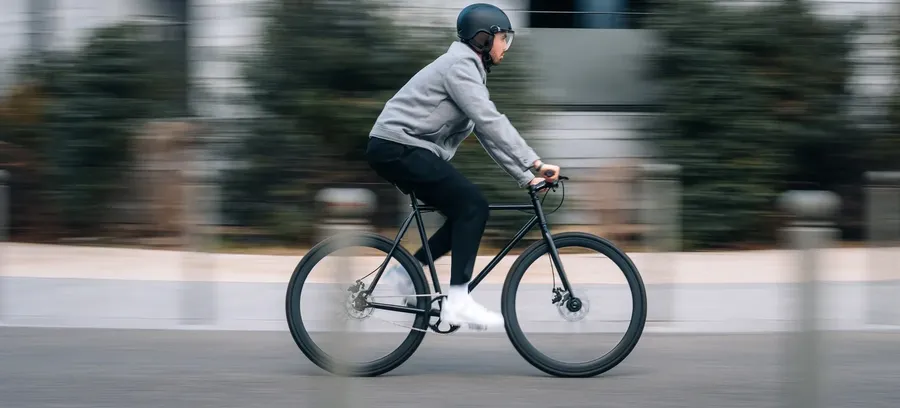 Une cycliste casquée CasR roule en ville devant des immeubles modernes