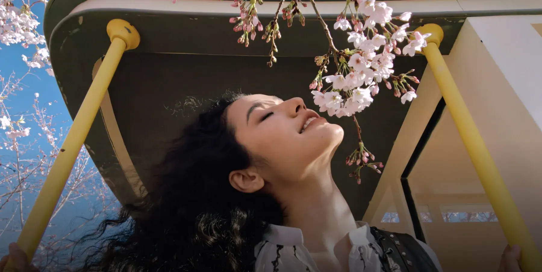 Jeune femme au soleil sous une balançoire et des branches en fleurs