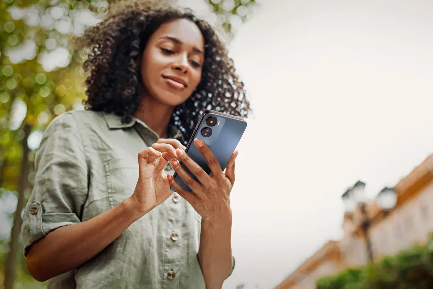 Jeune femme souriante utilisant un smartphone SPC en extérieur