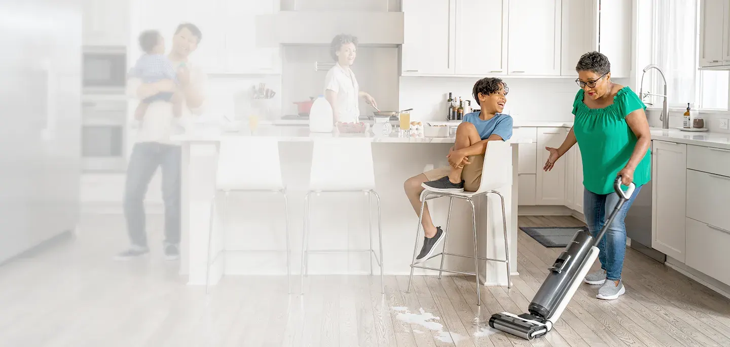 Famille dans une cuisine lumineuse, une femme passe un aspirateur laveur Tineco